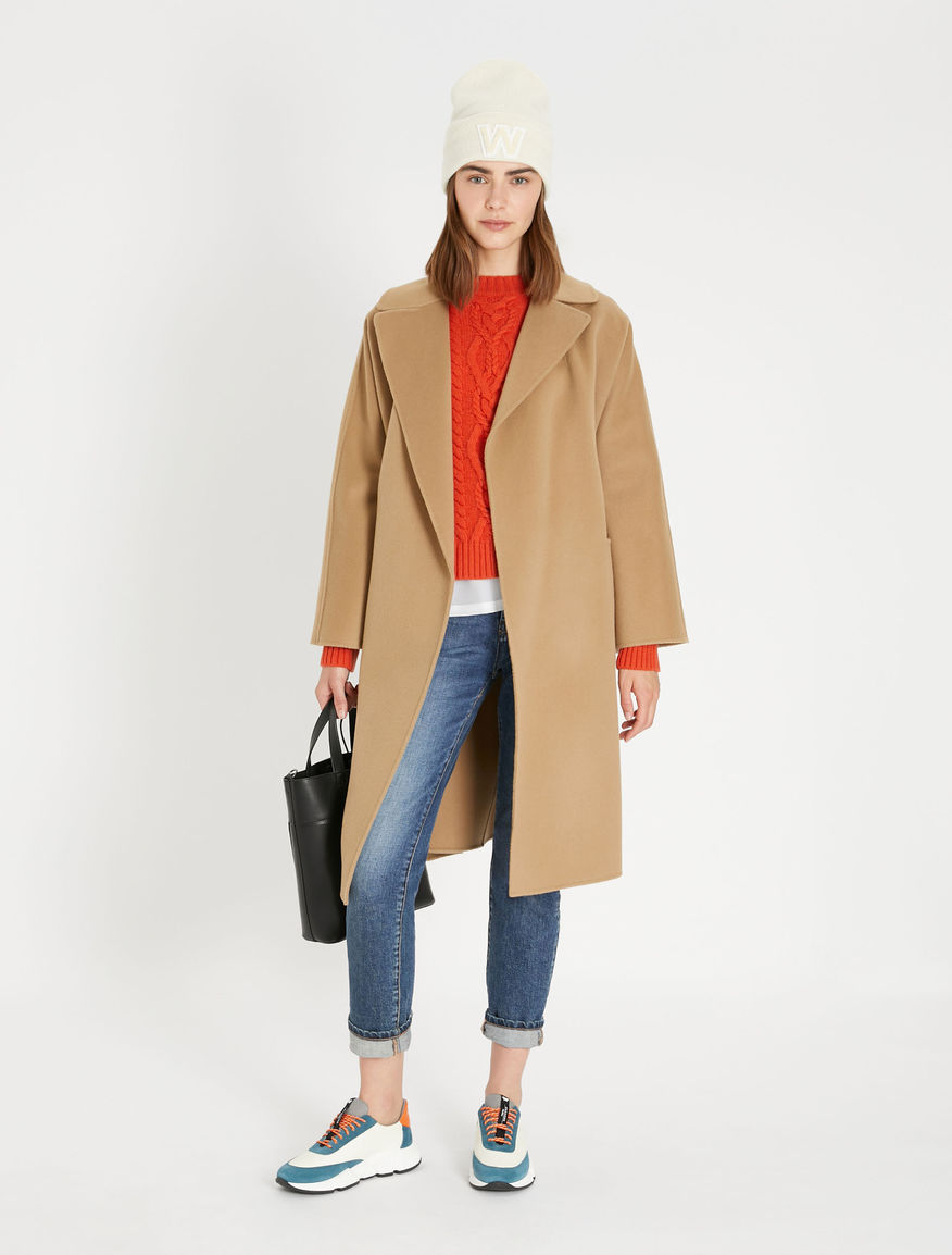 Maxmara weekend camel Rovo coat. Model wears wool camel coat over a red jumper and blue jeans, Autumn 21 trend